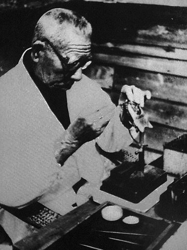 black and white photograph of Mikimoto Kokichi inserting a nucleus into a pearl shell